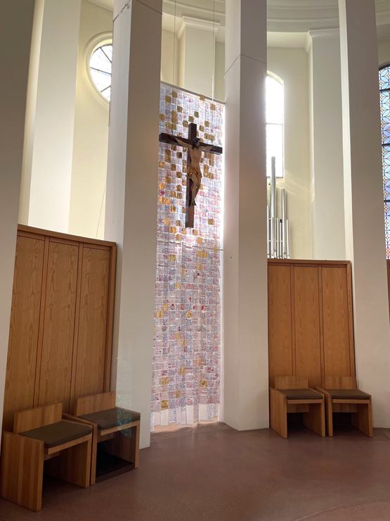 Das Hungertuch der Fastenzeit ist nun ein Ostertuch. Goldene Flächen durchziehen das Tuch hinter dem Kreuz. Je nach Lichteinfall beginnen sie zu leuchten – mal zart reflektierend, mal scheinen sie aus sich selbst heraus zu strahlend. Besonders in der Nähe des Kreuzes verdichtet sich dieses Leuchten.